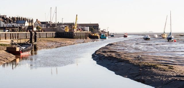 Old Leigh cockle sheds and moored boats on Leigh-on-Sea creek at low tide